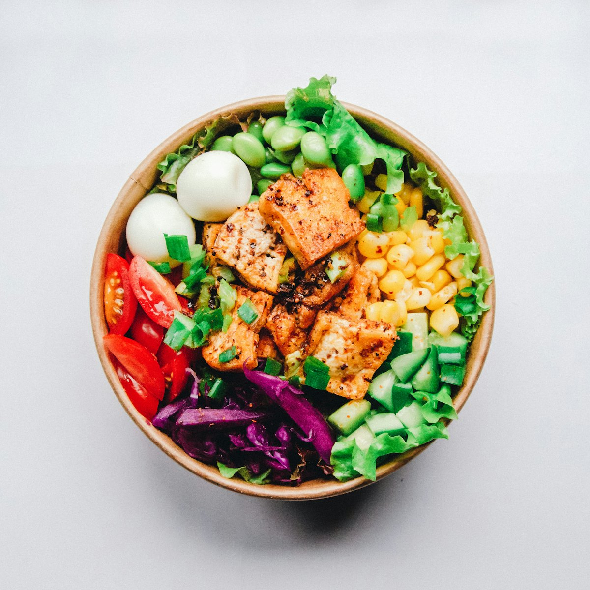 Bowl of greens, roasted tofu, egg, and vegetables