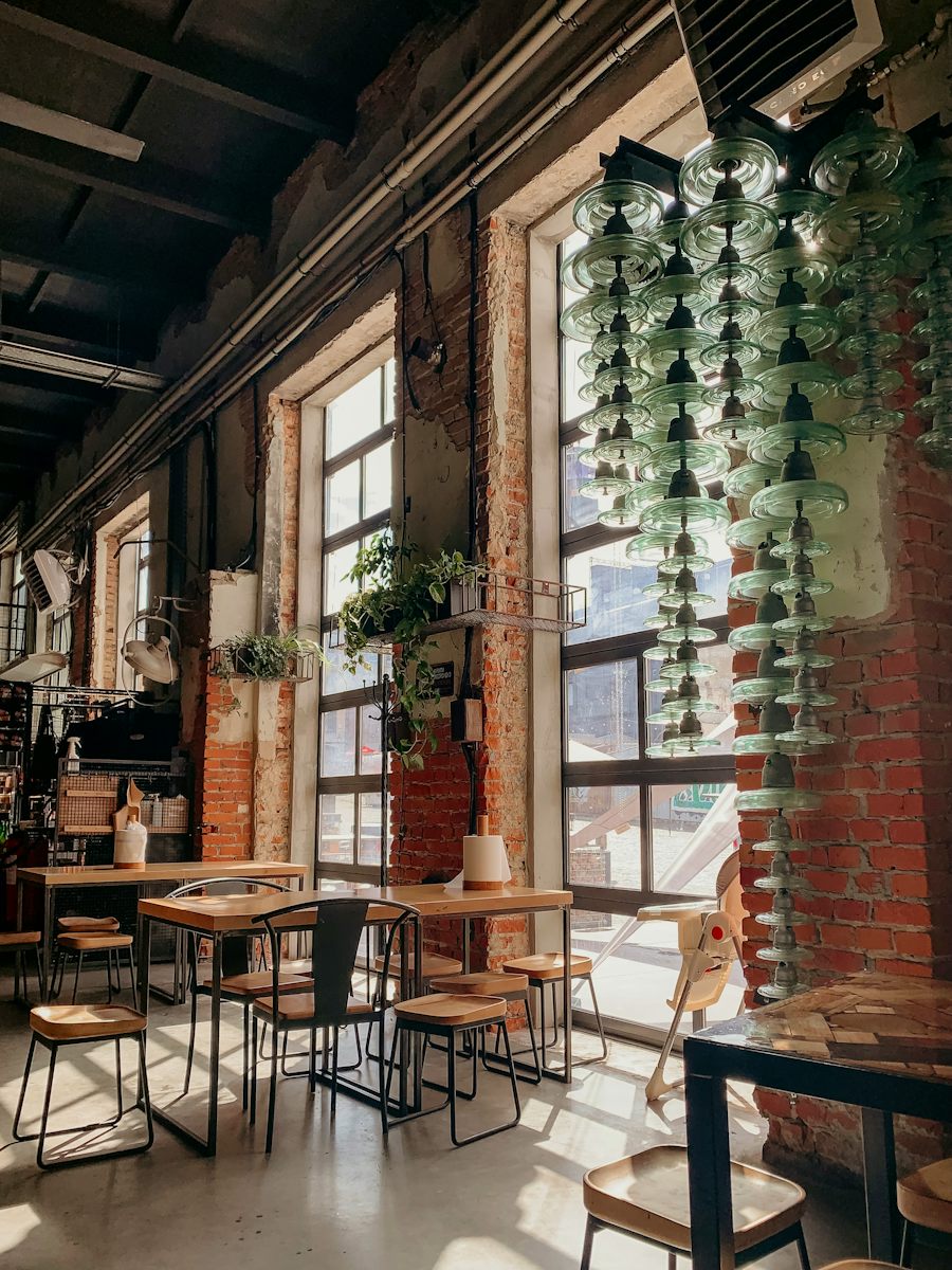 Cafe tables by tall windows and hanging plants